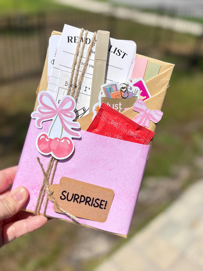 Brighten your reading life with this romcom-themed blind date with a book box. Inside you’ll find a feel-good mystery book wrapped in kraft paper, a reading log, fuzzy socks, and fun book accessories like annotation tabs and smut stickers. Ideal as a surprise box for women, bookstagram photos, or a book gift for romcom fans. This mystery box is a sweet treat for yourself or a joyful wife gift box to spark laughter and love.